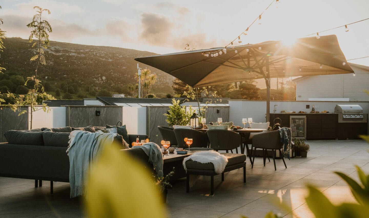 Outdoor dining and lounger area on a large decking with hillside views, and your very own outdoor kitchen at The Warren Resort & Spa